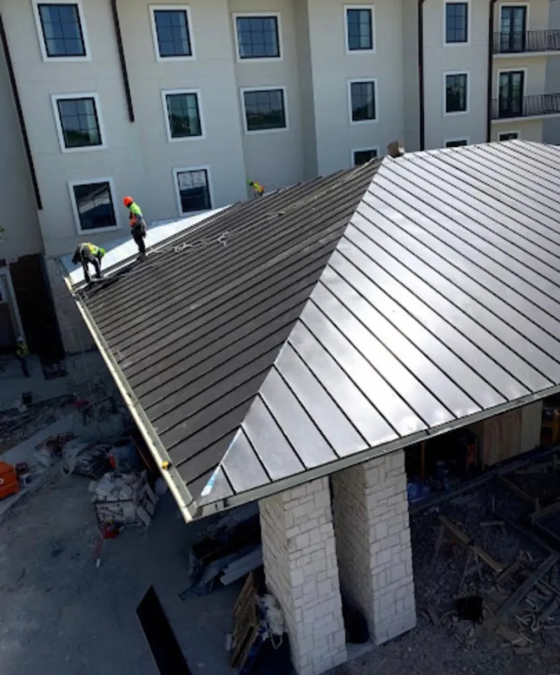 Crew installing standing seam metal roof panels on a commercial project in Telford